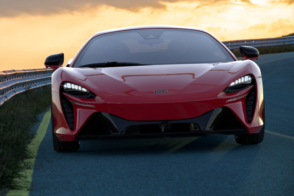 A red McLaren Artura driving on a mountain road.